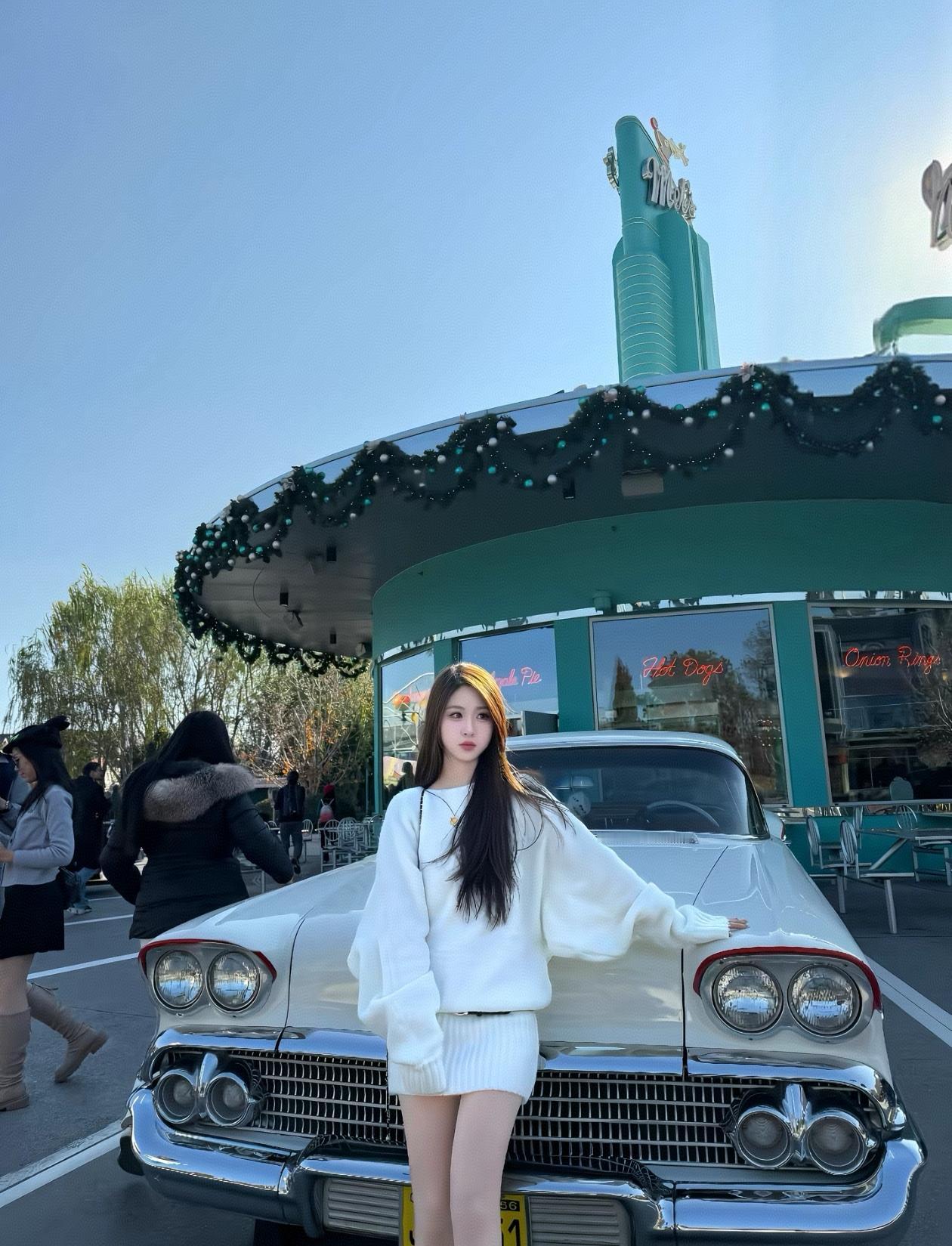 复古风车餐厅前，白衣少女倚靠老式汽车，怀旧气息扑面而来。