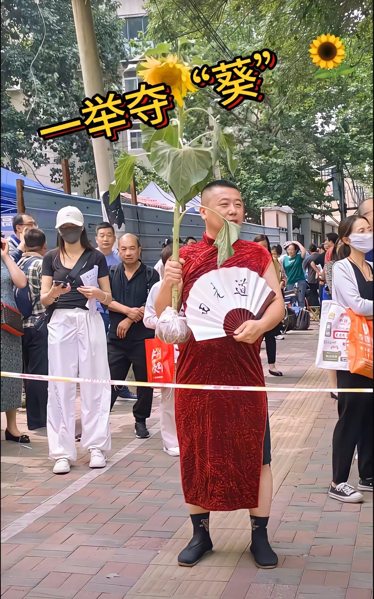 今年高考家长不拿甘蔗了，也不拿香蕉了改成拿向日葵了，妈妈不穿旗袍了，改成爸爸穿旗