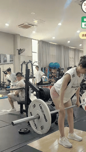 这讨厌的摄像头坏了我的好事……健身房里，一位身材姣好的女生正在做杠铃硬拉，一位