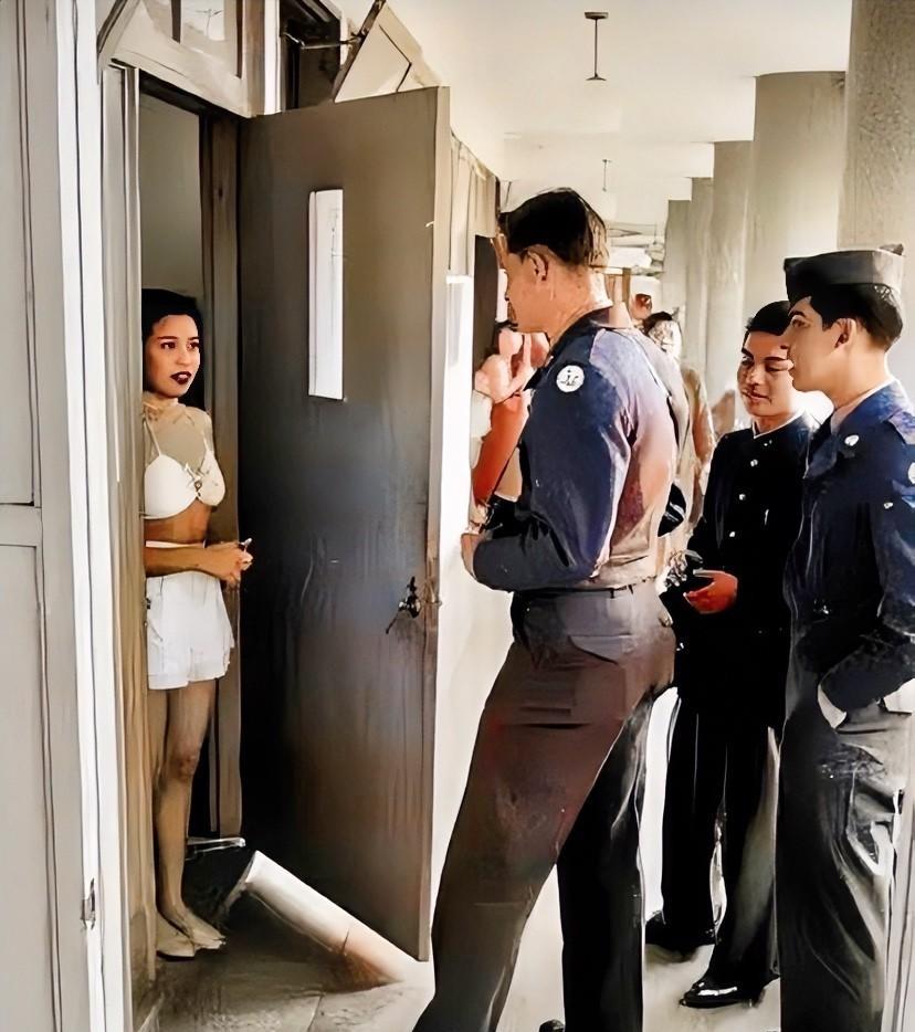 一个年轻漂亮的日本女子，正在与几美国大兵交谈。看起来，女人只有20多岁的样子，她