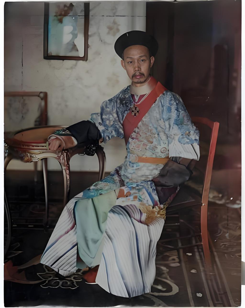 这张老照片里，张荫棠身着华丽的官服，头戴瓜官帽，稳稳当当地坐在椅子上，左手随意搭