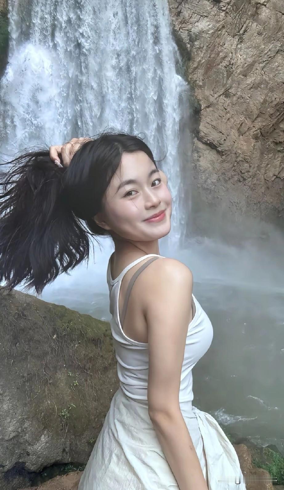 瀑布前，少女轻抚秀发，笑靥如花