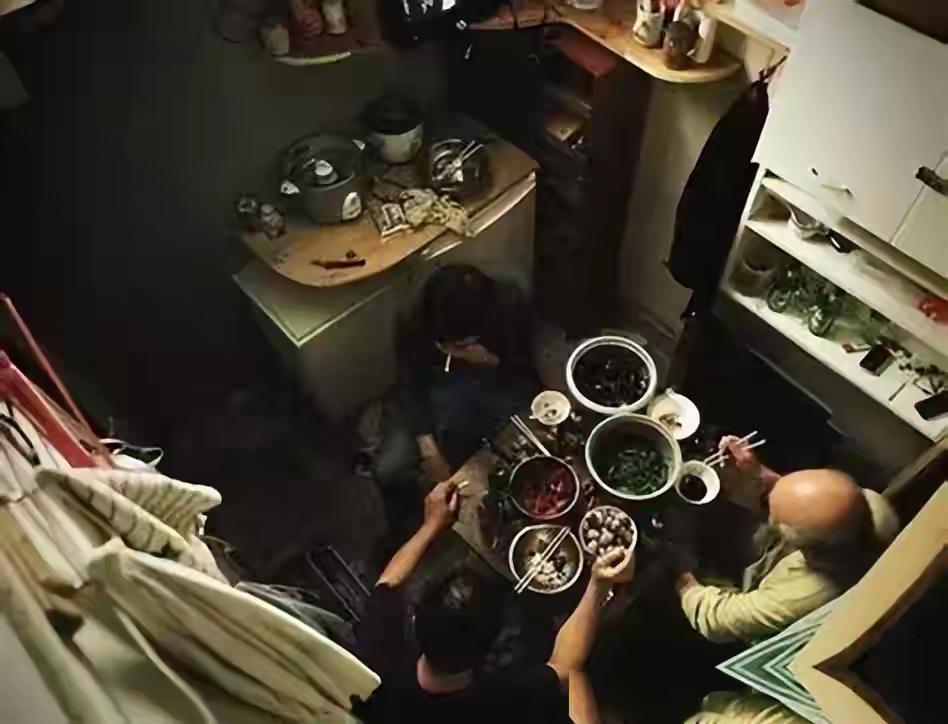 一张布帘子，隔开的不是房间，是两种人生的距离。左边男人在咳嗽，右边女人在翻身，中