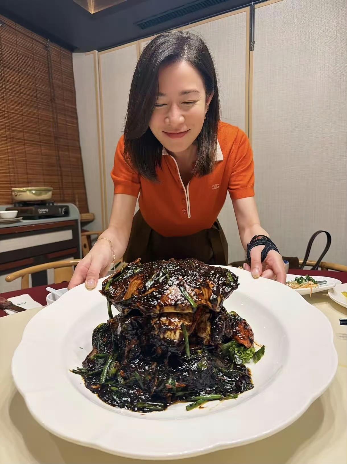 佘诗曼与好友同游新加坡，品尝巨型大闸蟹，蟹壳竟比脸庞还大！饱餐后她满足地捧着肚子