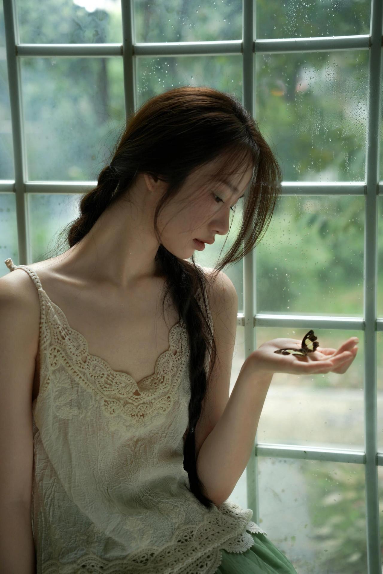 照片里的少女，摄影师定格了眼神低垂，似在专注地拨弄着自己的辫子，神情透着一丝淡淡