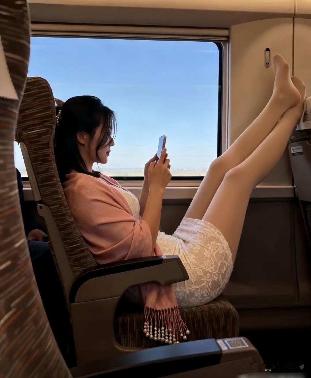 高铁上认真看手机的美女，这脚都搭在前排座位头上了。虽然自己松弛舒服，可考虑过其他