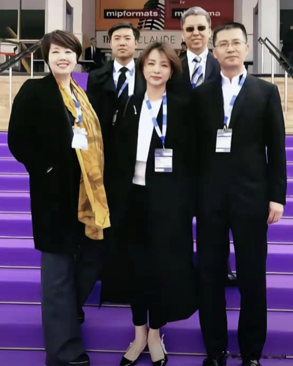 五个人的合照，董卿站在最中间，她穿的特利落，一件黑风衣配黑裤子，往那一站，风衣的