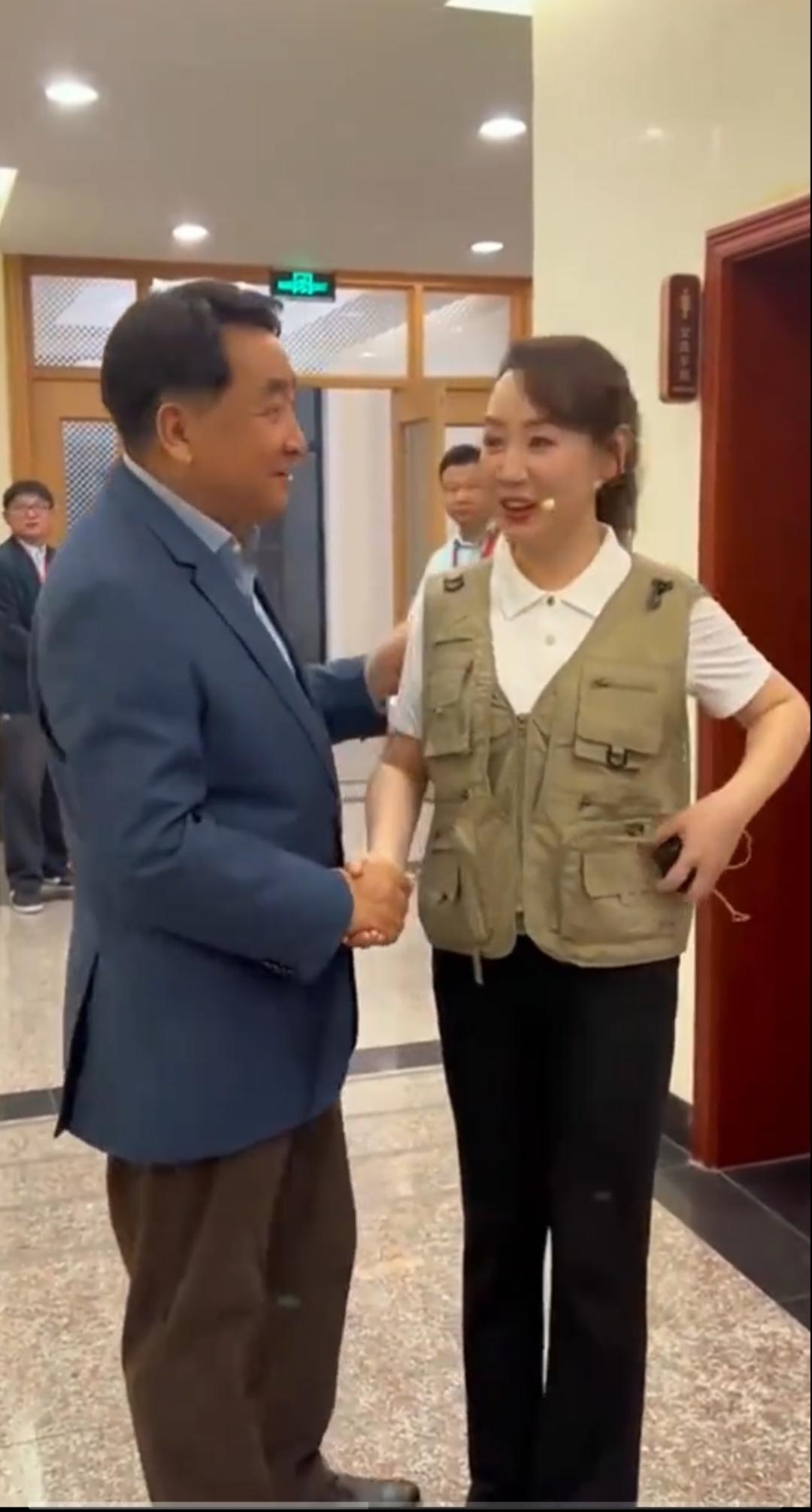 相声名家姜昆，与主持人手牵着手，姜昆老师还轻轻搭着她的肩膀，面对面开心聊天。