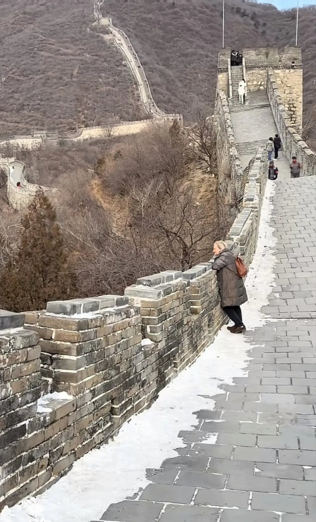 这位女士依偎在城墙边久久不愿离去。她在想什么呢？