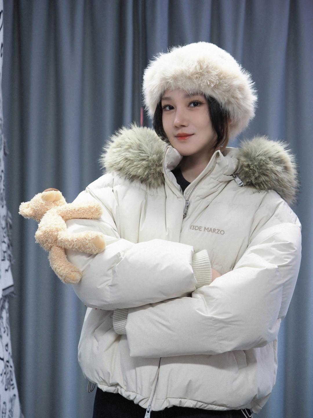陈小纭的冬日新造型，把可爱与温暖的氛围拉满。米白色羽绒服搭配同色系毛绒帽，蓬松的