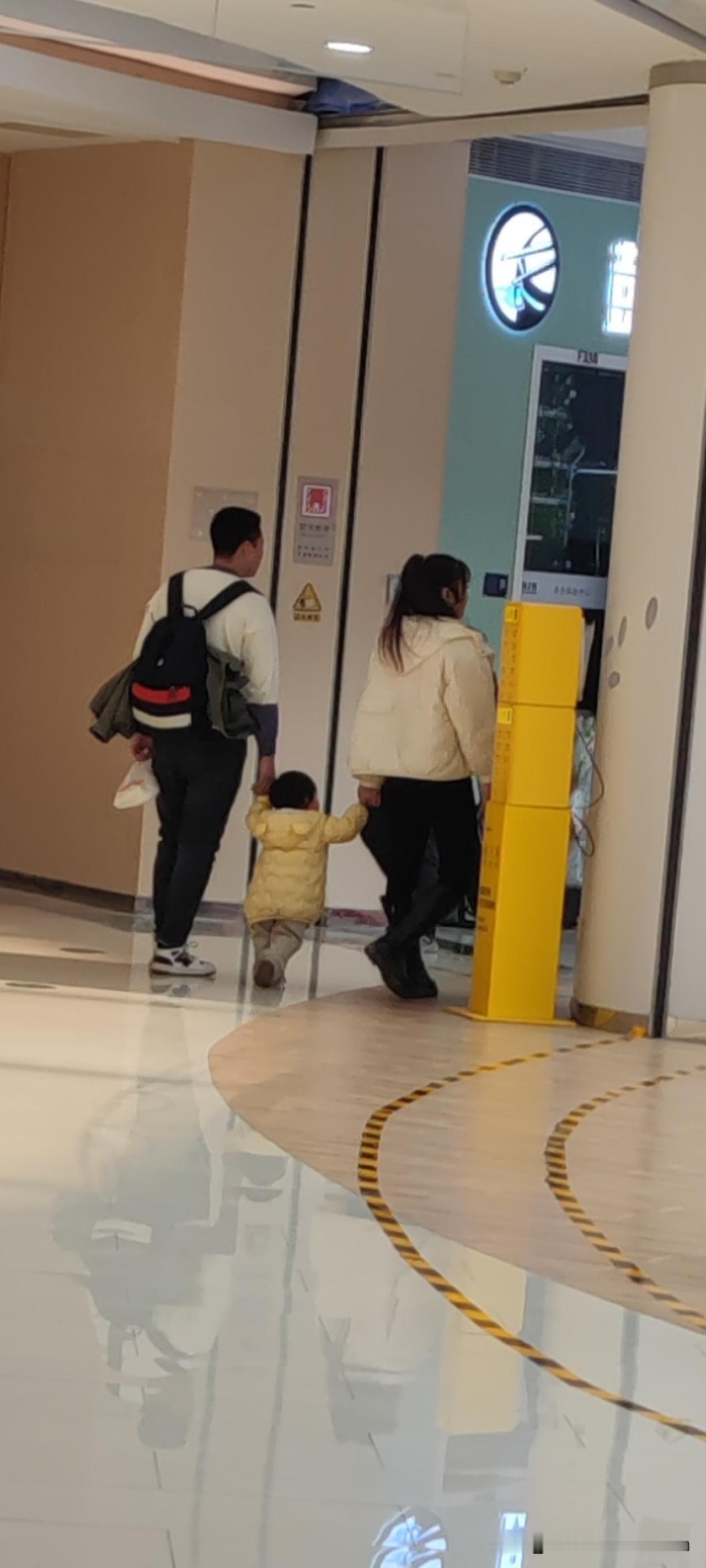 一对夫妻带着孩子走着走着，孩子突然张开小手让妈妈抱。妈妈立马蹲下说：不行，妈