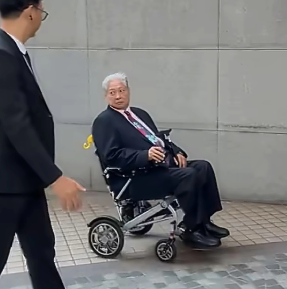 洪金宝坐着轮椅出席活动身穿黑色西装梳着标志性大背头，精神看着还不错，但大家第一