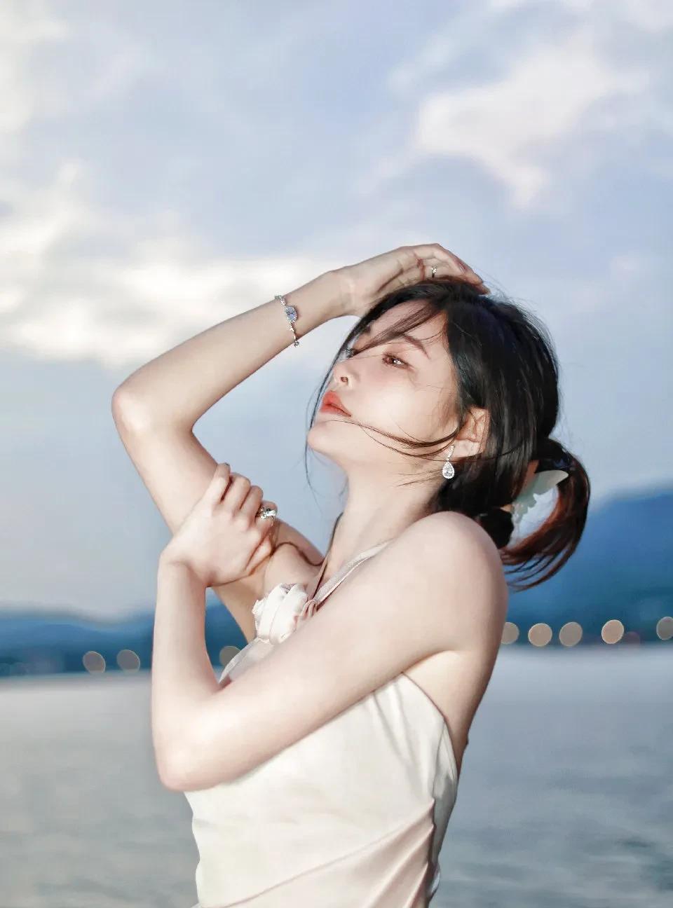 许佳琪海边写真，一袭挂脖裙优雅动人。柔和的色调与海边景致相融，挂脖设计露出精致肩