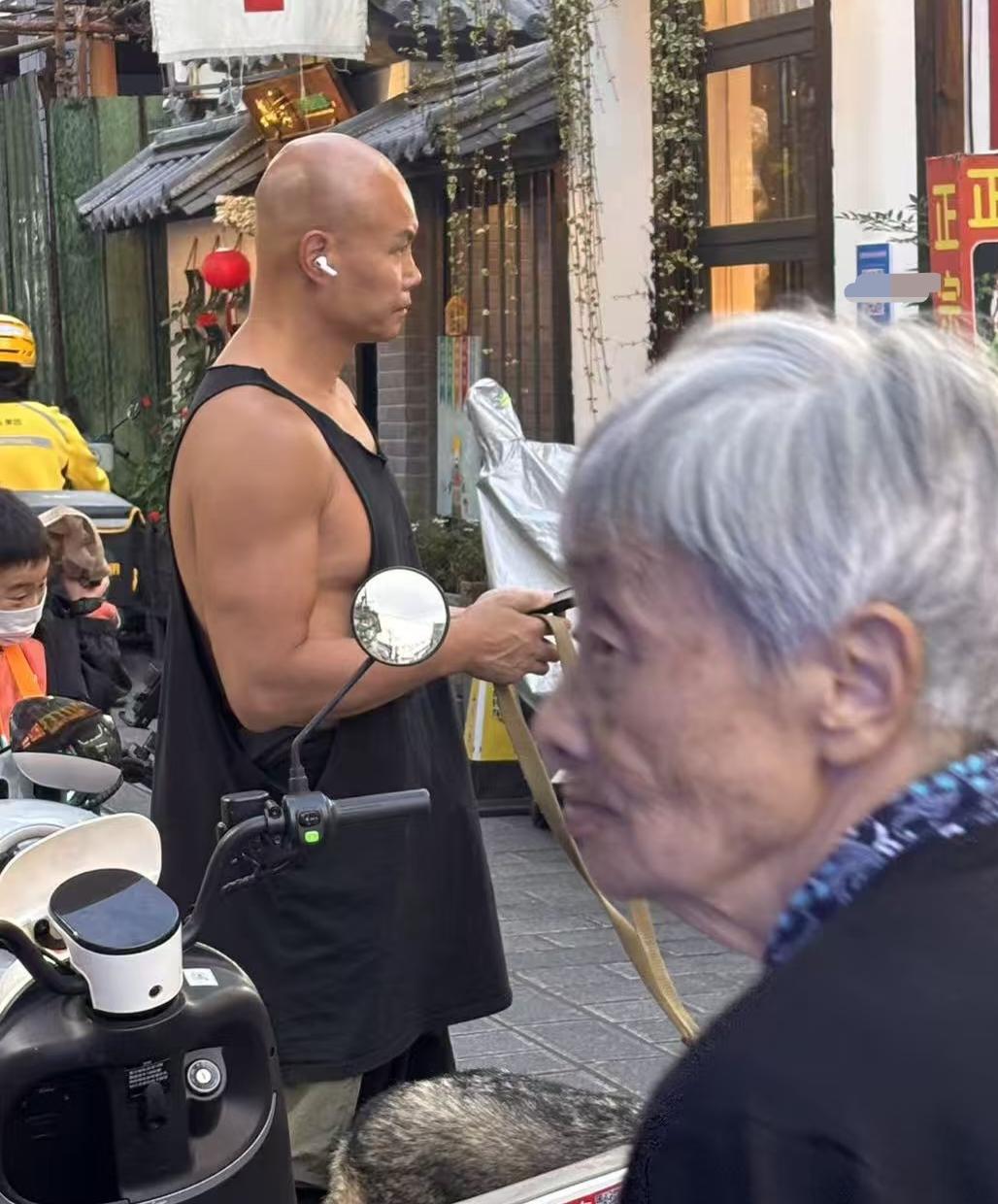 51岁乐嘉在云南大理古城遛狗被偶遇，他牵着一条巨大的捷克狼犬，穿着一条黑色背心，
