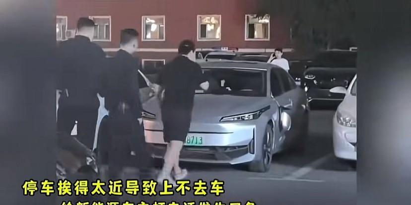 这下惨了！新能源车停车靠隔壁白车太近，黑衣服车主打不开车门，打电话给车主想让挪下