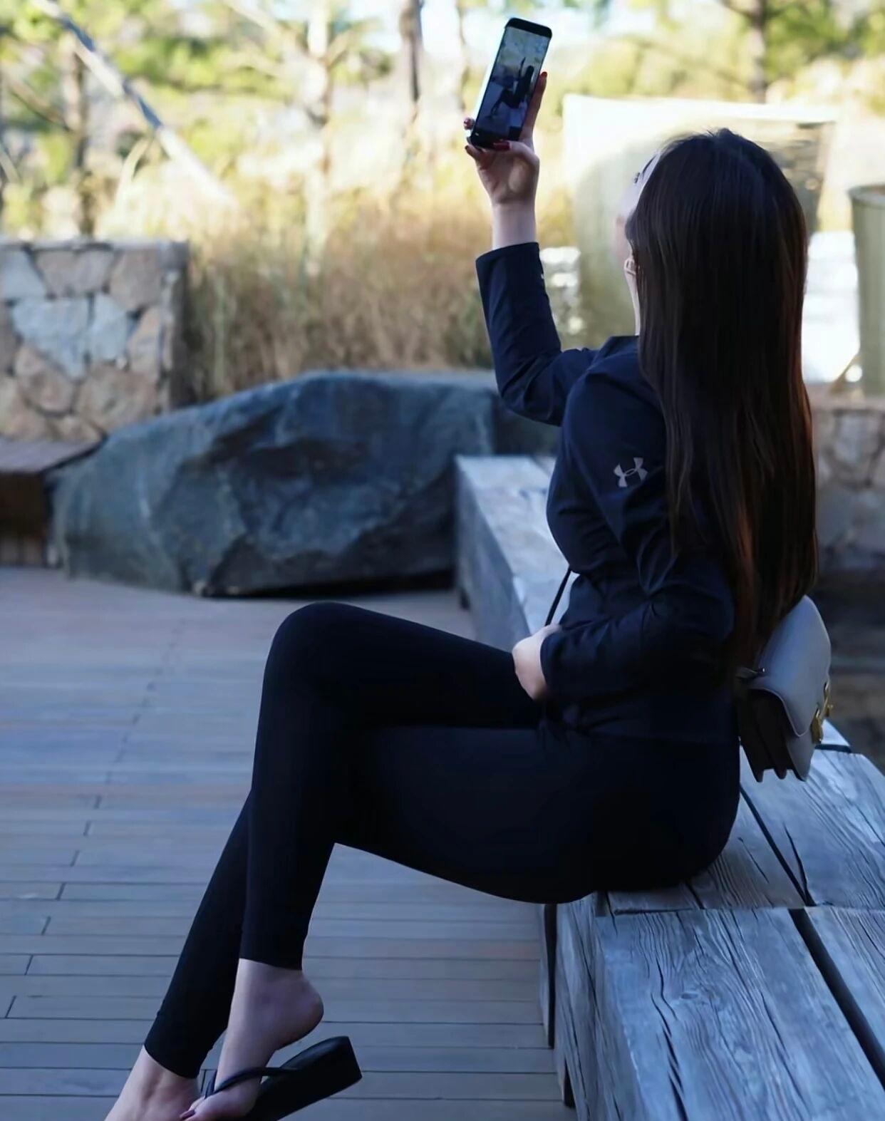 身材安德玛的运动衣服的健美爱好者，长发飘飘，在公园自拍。户外自拍，享受阳光与自然