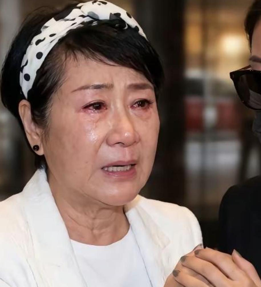 全场穿得黑压压，只有狄波拉一身白西装站在人群里。镜头扫过来的时候，评论区直接开