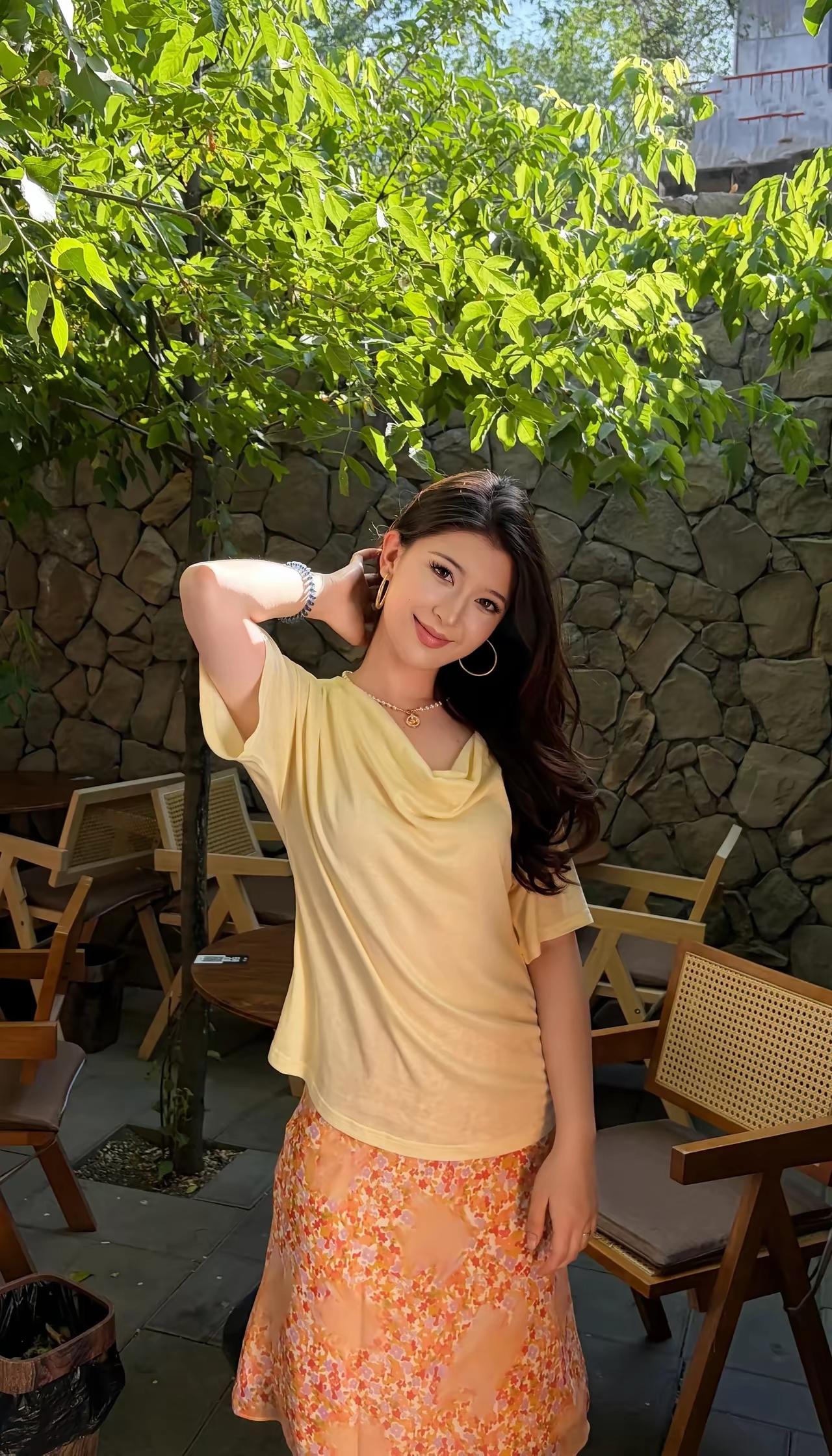 阳光下的少女，清新自然，花裙飘逸，石墙绿树相映成趣。