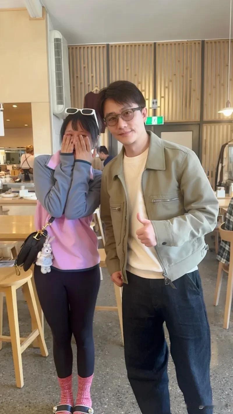 黄轩现身新西兰，戴着眼镜，穿着一件浅色外套，身材清瘦，肤色好白，气质斯斯文文的，