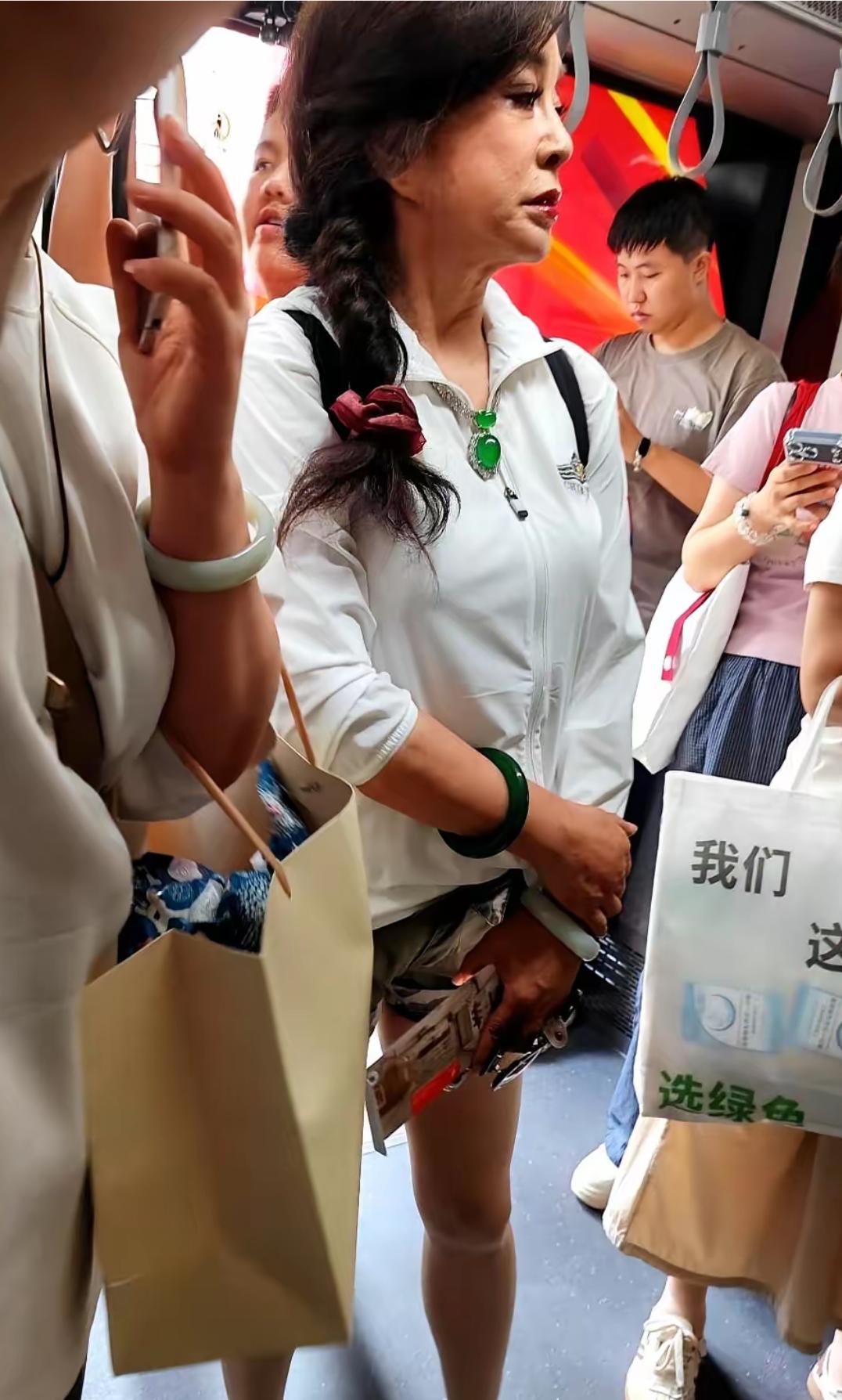 刘晓庆在机场被偶遇，上身穿着白色休闲服，牛仔短裤，背着背包，扎着麻花辫，化着浓妆