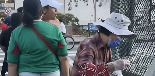 洛杉矶骚乱的街头，一位中国大妈却引起了大家的注意，与混乱人群形成对比，一些人拿着
