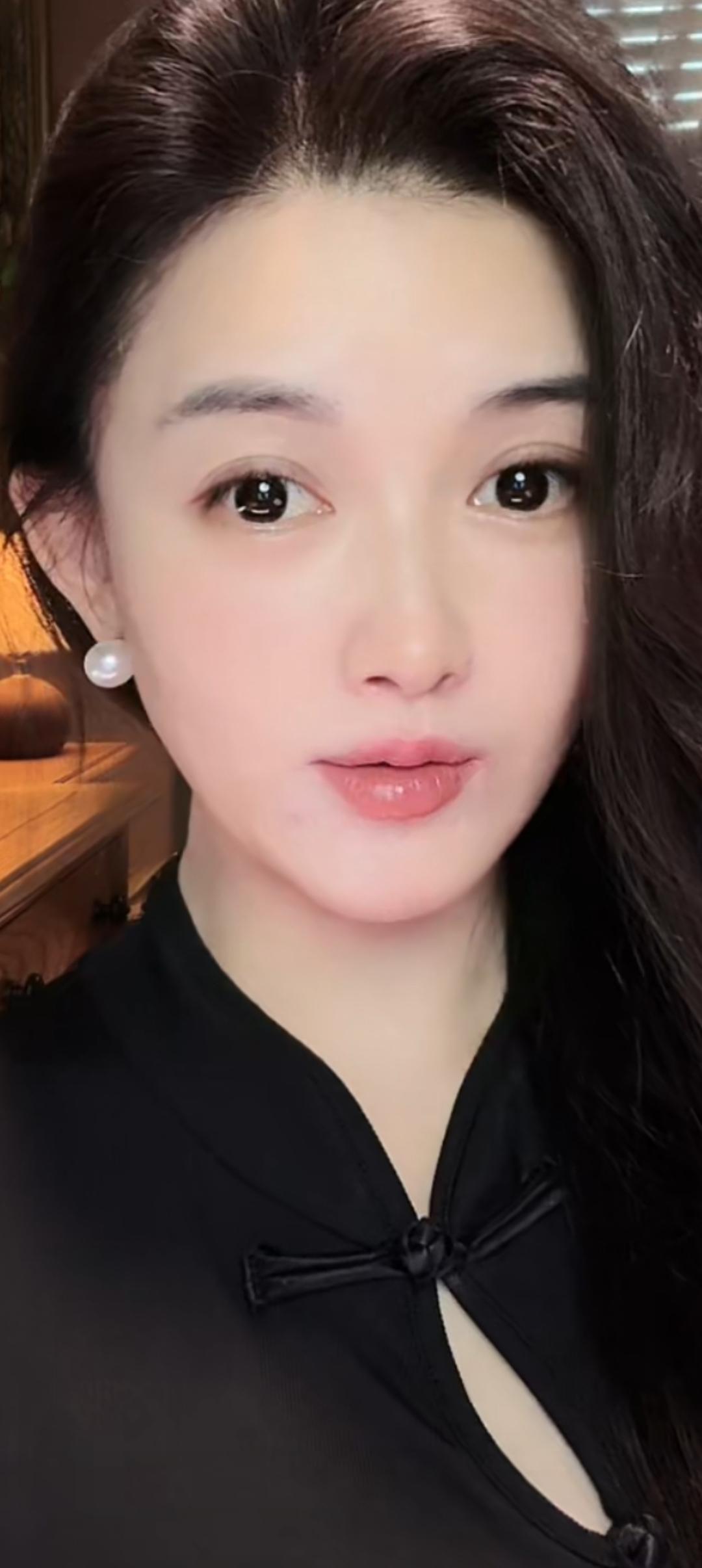 这位美女穿着黑色上衣，戴珍珠耳环。