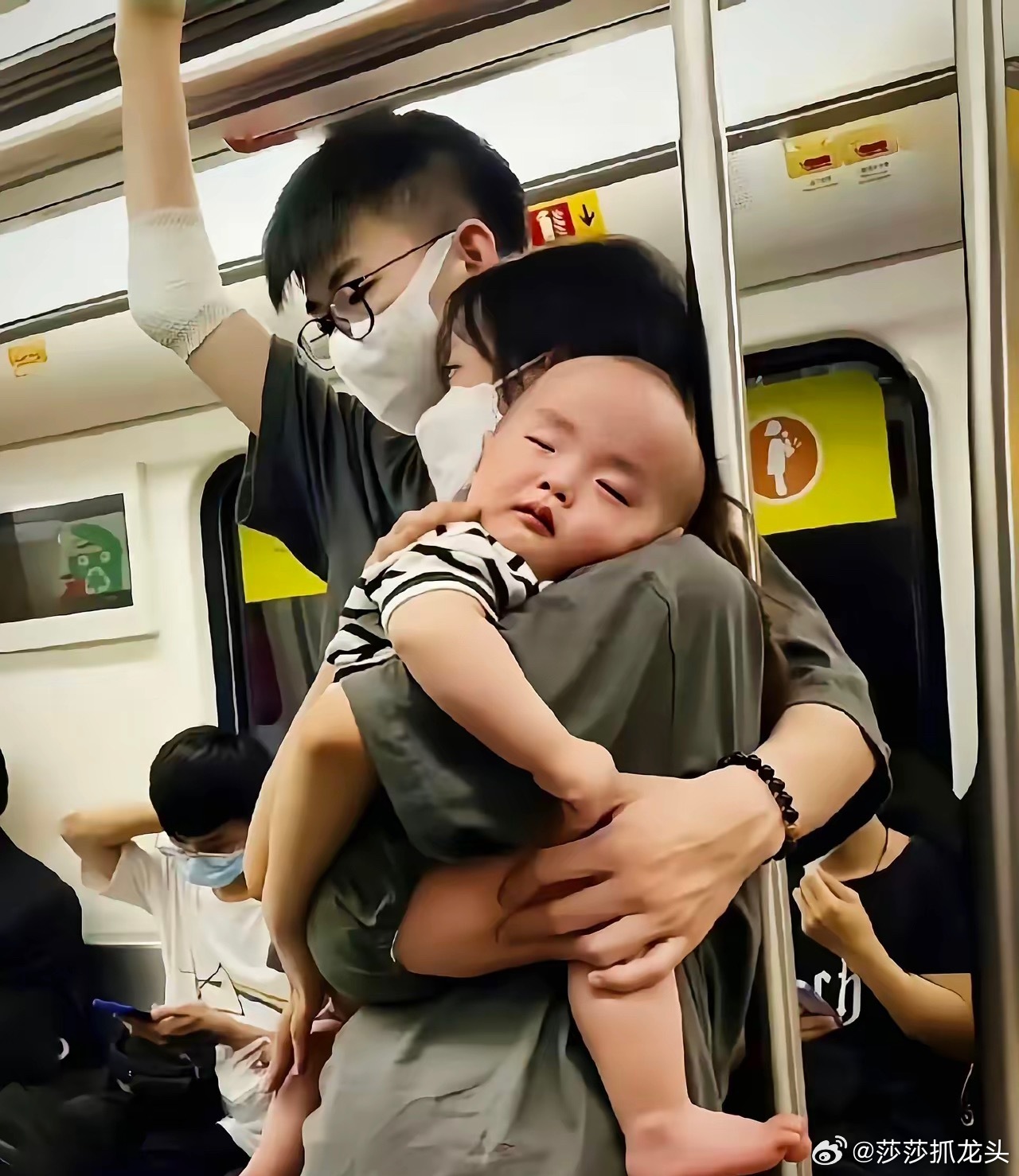 公交车上，一位丈夫张开臂膀，稳稳环着妻子与怀中的孩子。妻子将脸颊轻轻贴在他温热的