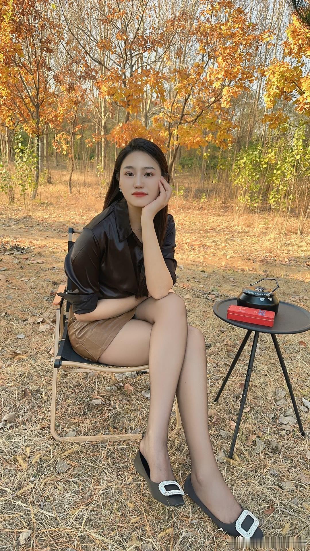 一个美女坐在户外享受秋天的阳光。