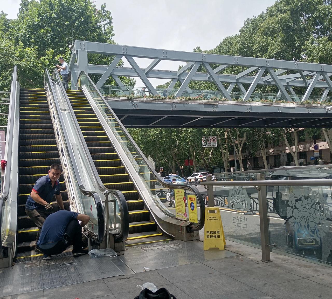 雨后洛阳天桥的电梯出故障了，技术人员正在维修。为了市民出行安全，天桥电梯最好安装