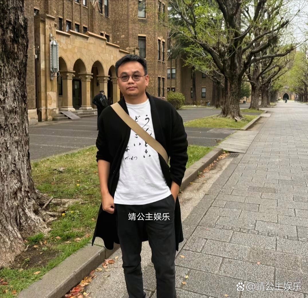 54岁袁立和老公梁太平在日本东京大学内赏樱花，她身穿黑色长大衣，背着名牌包，气质