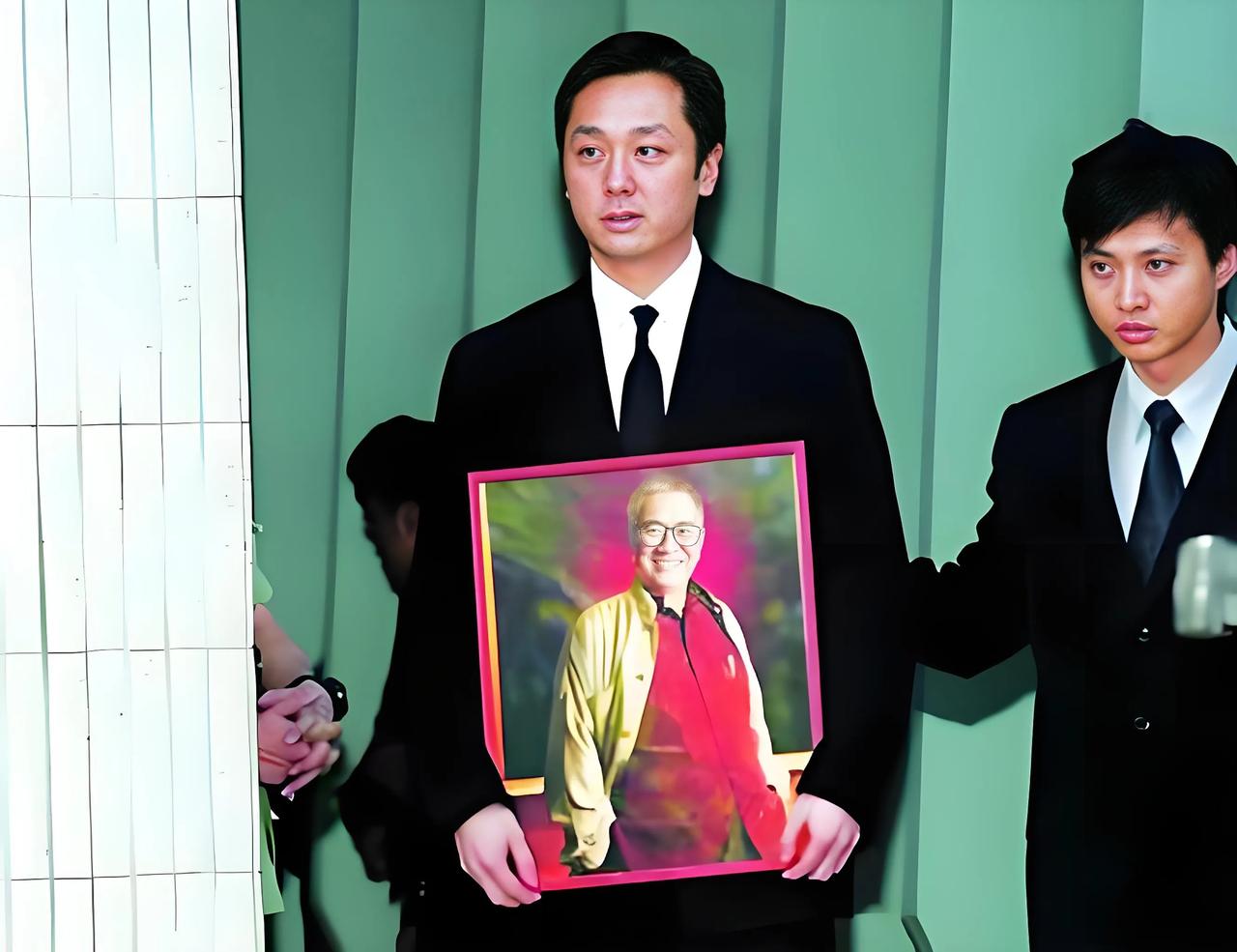 2004年，黄霑葬礼上，一张珍贵的留影，长子黄宇瀚手捧黄霑遗像，走出举行仪式的礼