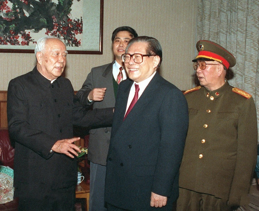 照片中江同志满面春风，他身后是军委副主席刘华清，参加过长征的老红军，刘邓大军走出