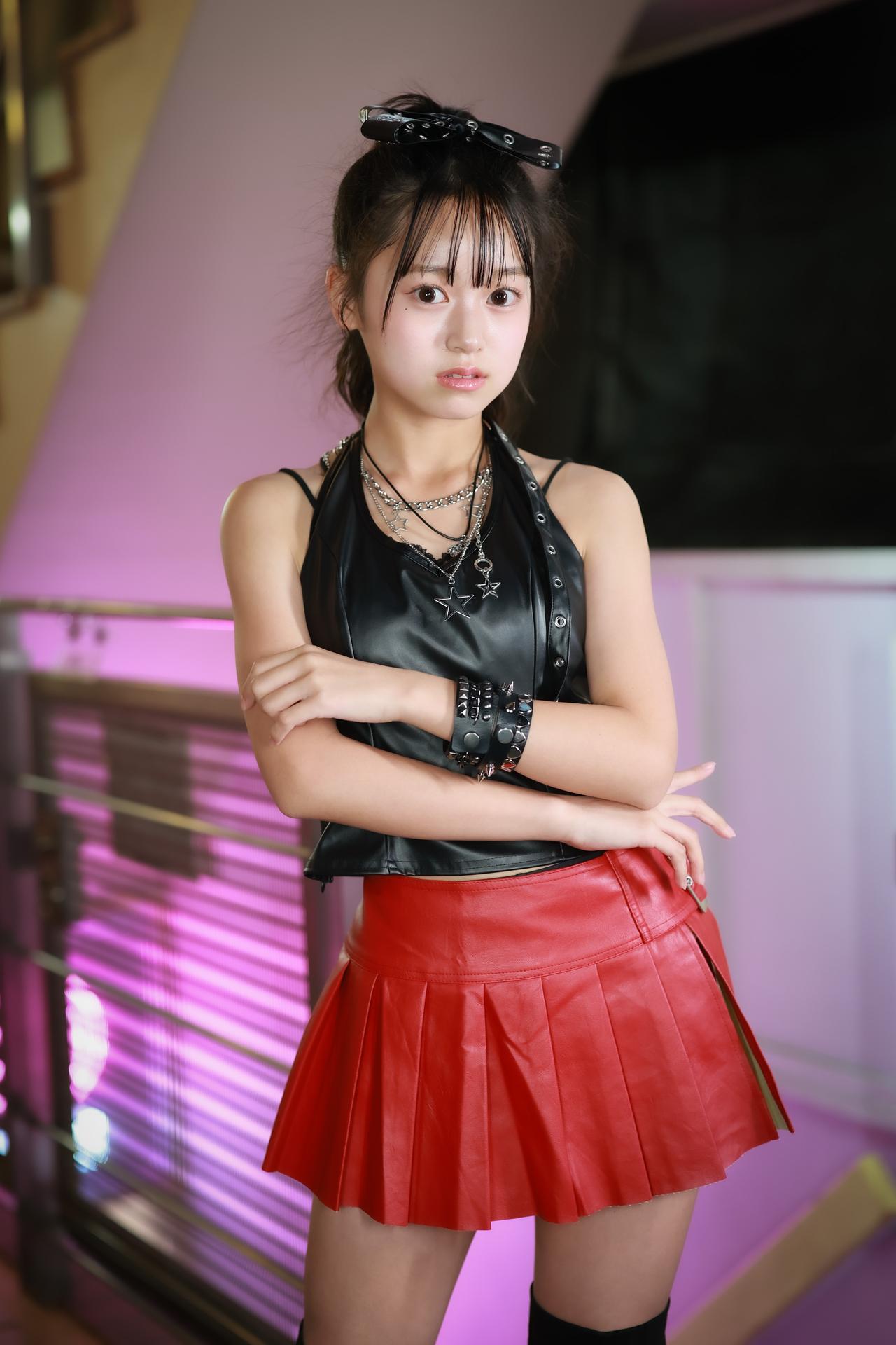 红裙映粉墙，少女倚栏旁。