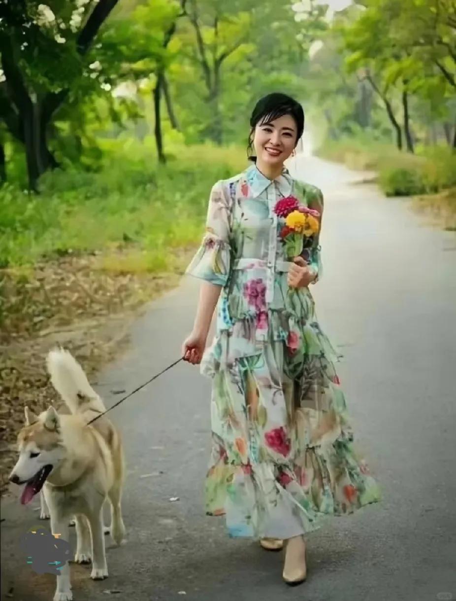 宝子们，快来猜猜这是谁！她一袭碎花长裙，手持缤纷花束，悠然牵着狗狗漫步林间小道。