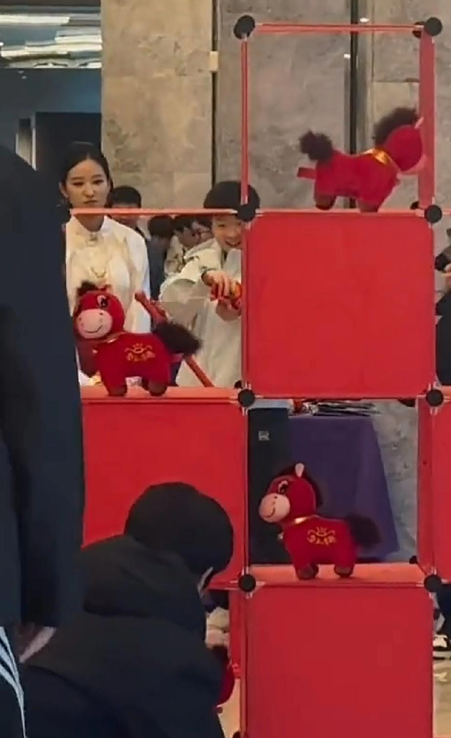 红红火火的可爱小马，在展台上。莎莎看的目不转睛。指着小马对旁边人说，真可爱。放桌