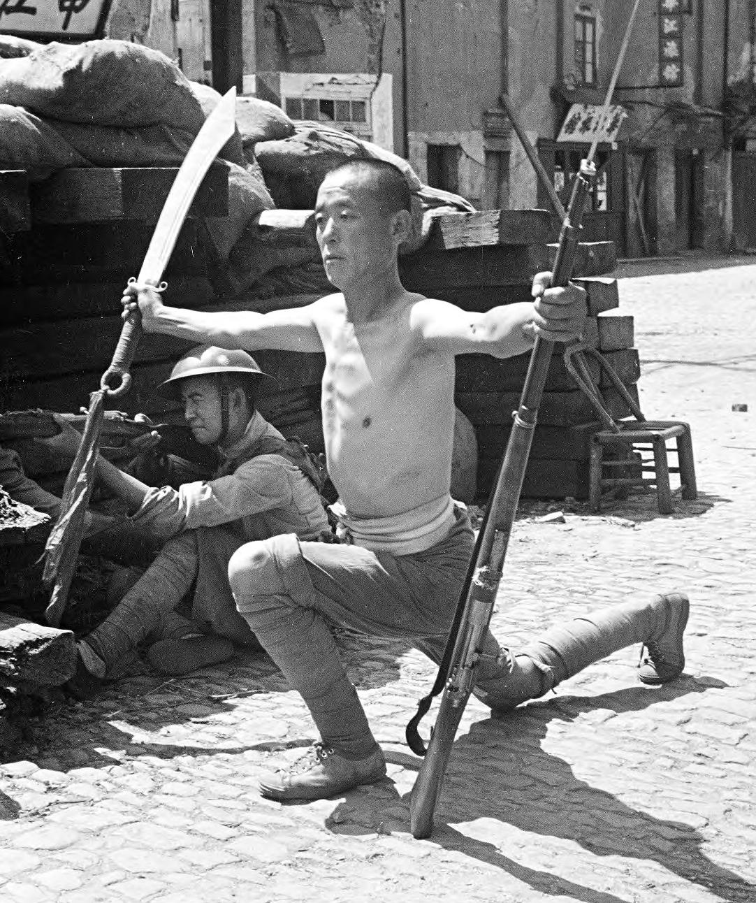 1937年，上海淞沪会战，一名老兵赤膊上阵，向阵地对面的日军展示出自己的大刀和步