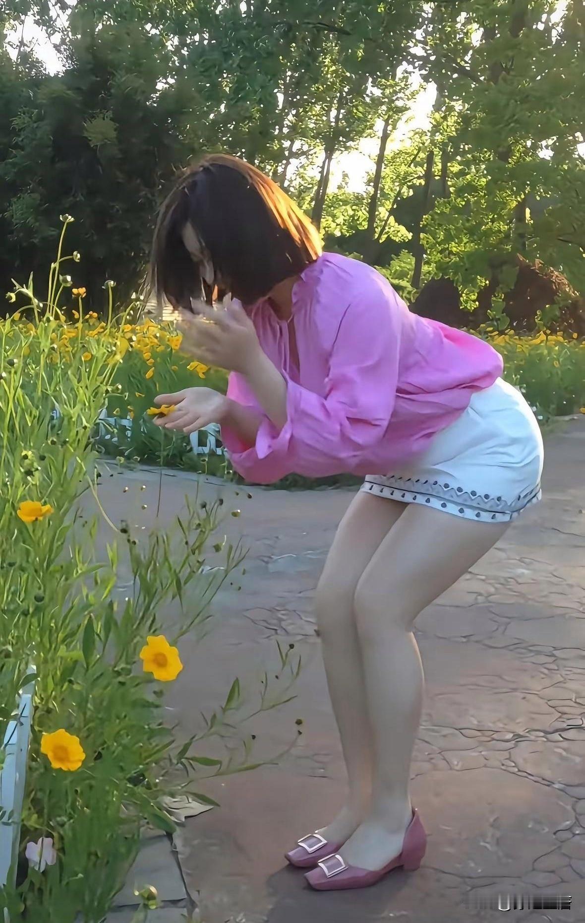身段出众，皮肤白皙在阳光下透亮发光，一身浅色系连衣裙，大长腿若隐若现。微微低头轻