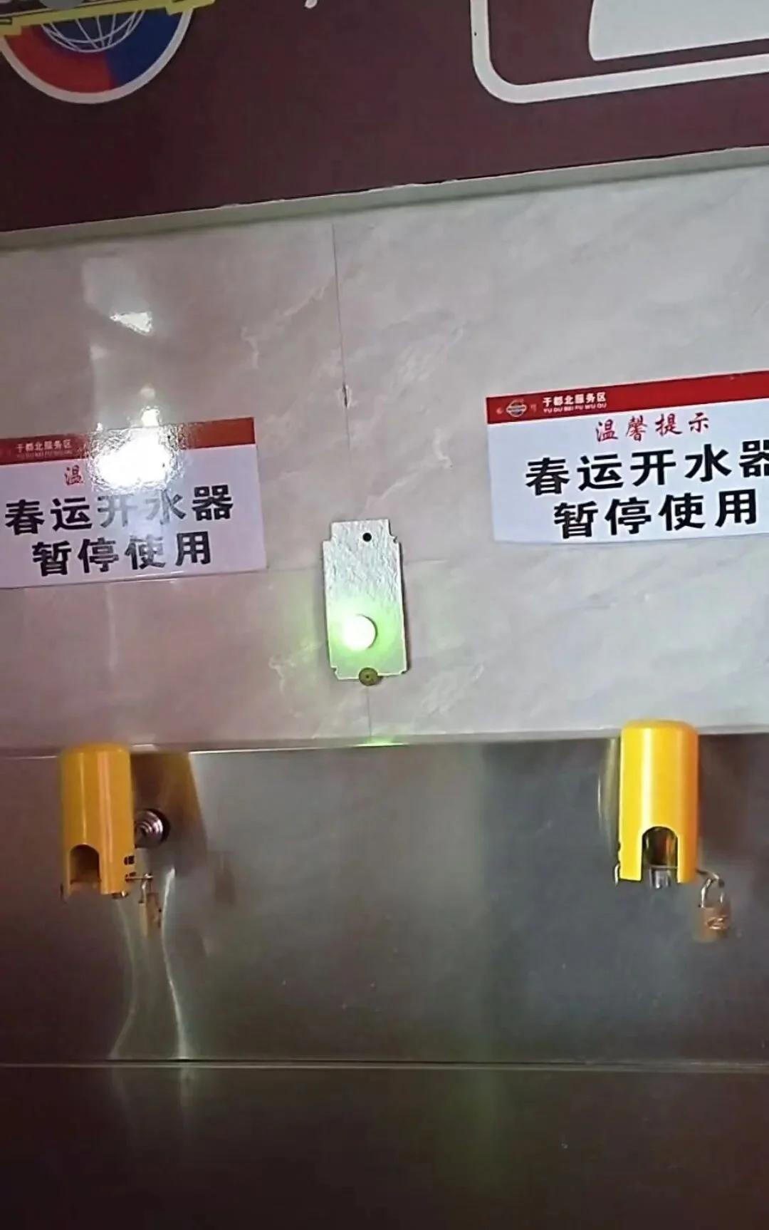 江西一高速服务区。有两个水龙头被锁住了，贴着温馨提示“春运开水器暂停使用”。负