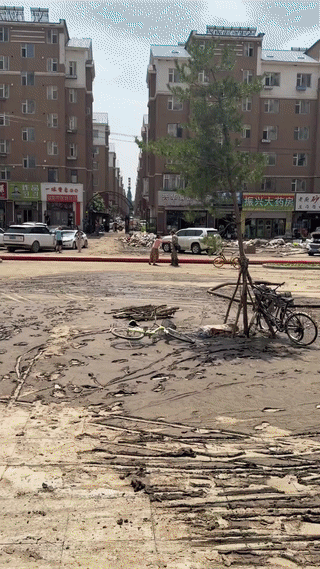 吉林敦化街头。一位当地的大妈给参与洪捞灾害救援清理工作的两名解放军战士送食物东