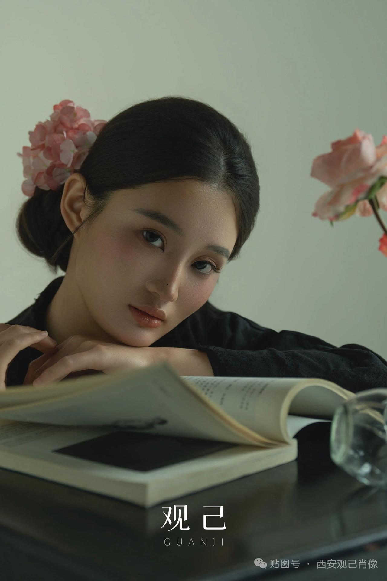 一个美女在看杂志，旁边有花。