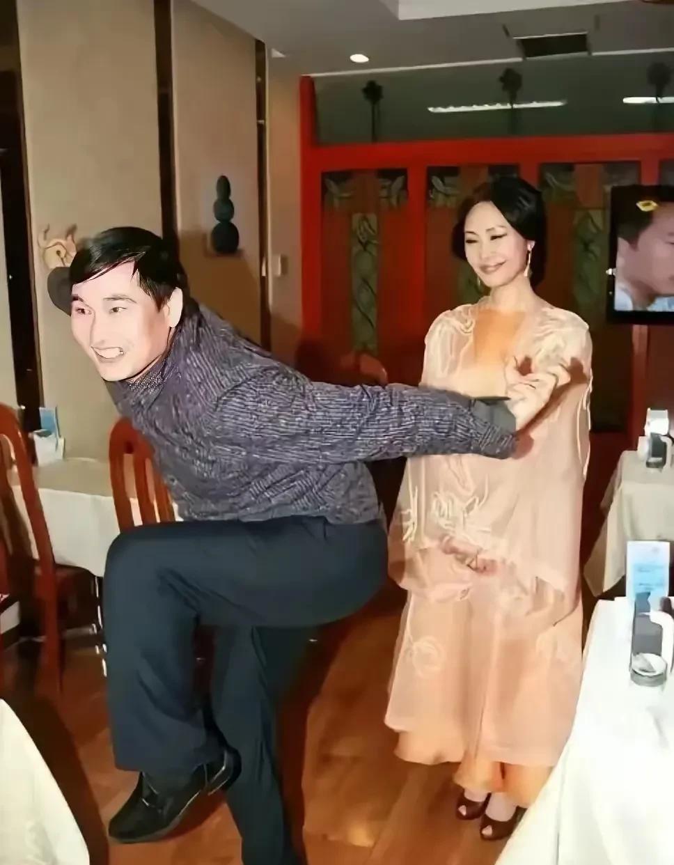 这是大衣哥在摆着一个搞笑动作，于文华站在后面穿着一身连衣裙，脚踏一双高跟鞋，脸上