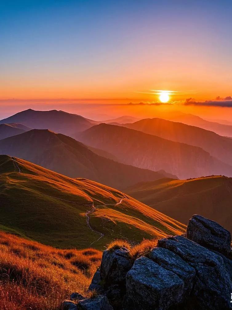 于武功山之巅，看夕阳西沉，天空从淡红渐至深红，云朵幻化成骏马绵羊。日落沉溺于云海