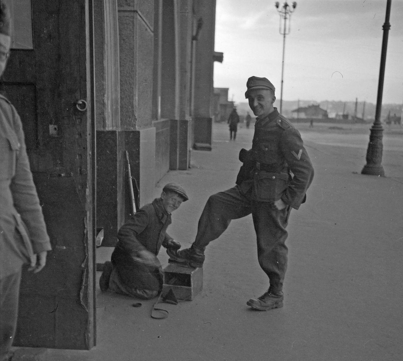 沦陷区艰难谋生——1942年，基辅。一名苏联少年正跪在地上，给一名德军士兵擦皮鞋