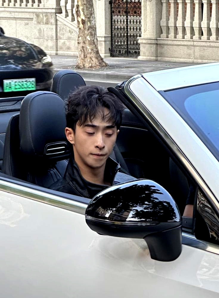 上海新天地街头，一辆库里南缓缓停下，伊能静儿子恩利推门下车，黑色大衣配一身银饰，周围路人举着手机拍个