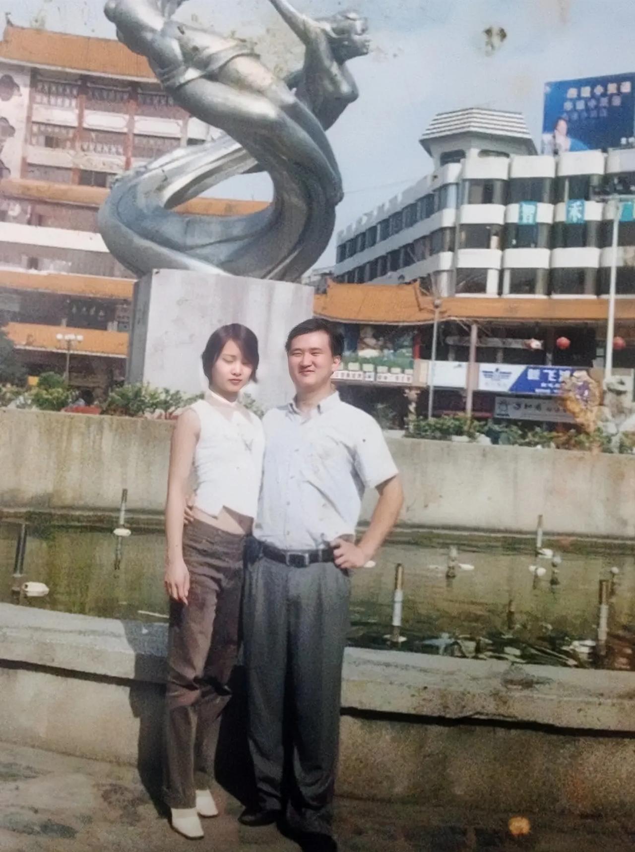 20多年前贵州兴义，一对年轻夫妻在街心花园喷水池前留影，姑娘的打扮很潮。小伙子