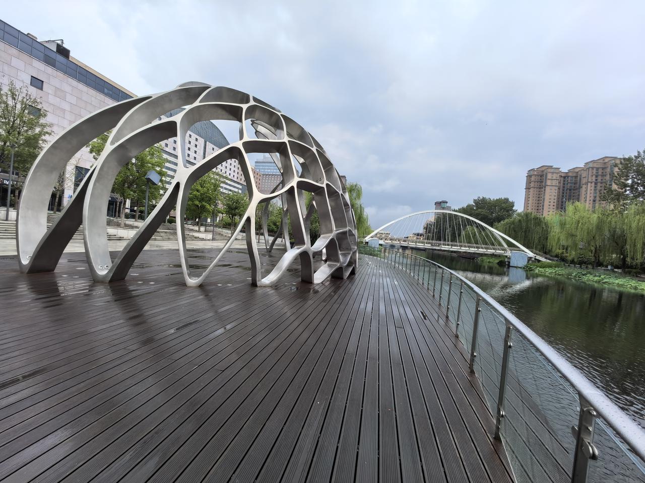 河畔闲行金属穹架撑开城市的留白古塑人马，驮着旧日风尘河水静静漫过岸