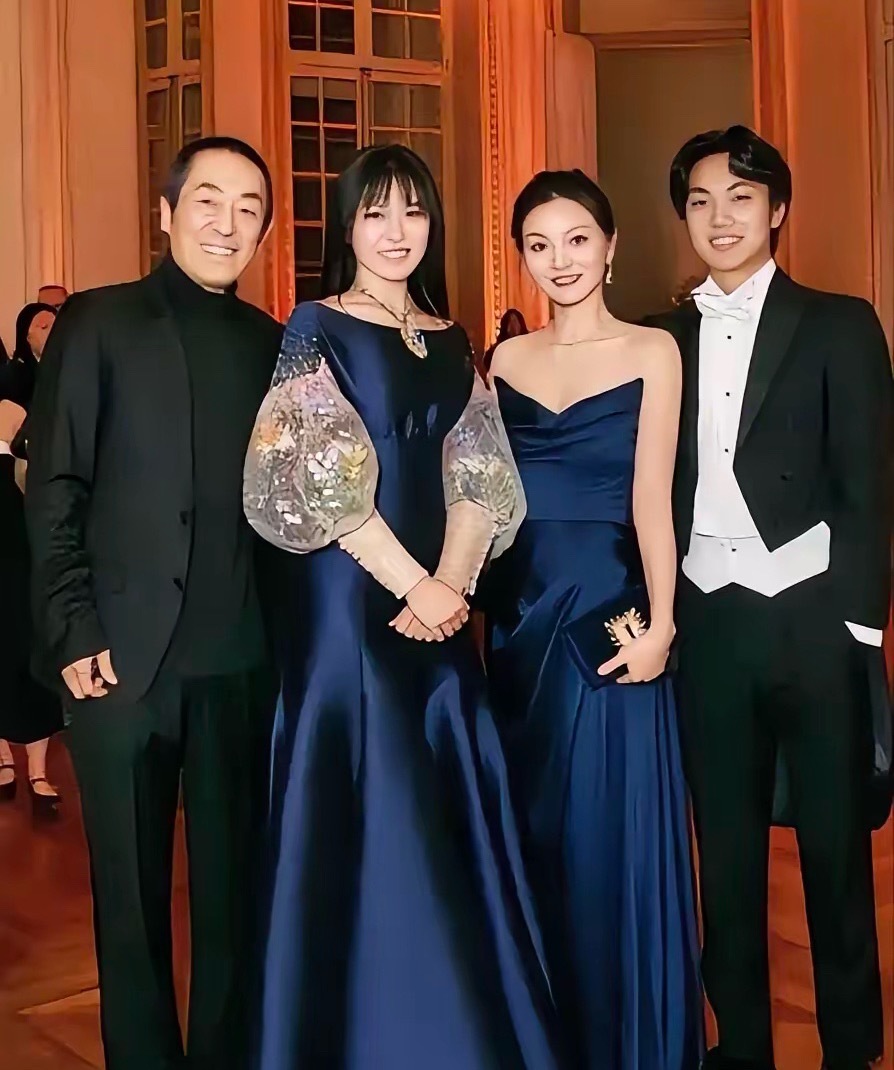 张艺谋一家四口的合影，女儿跟妈妈陈婷穿着同色系的礼服裙，身高比妈妈高，但颜值一般