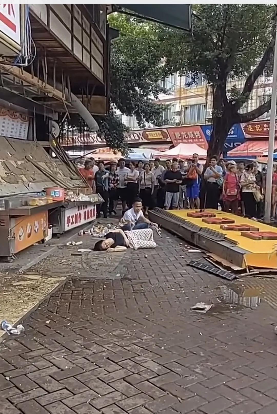 天降横祸，牌匾掉落，猝不及防，女子遭殃。广西梧州某街道，店铺林立，人流如织。路