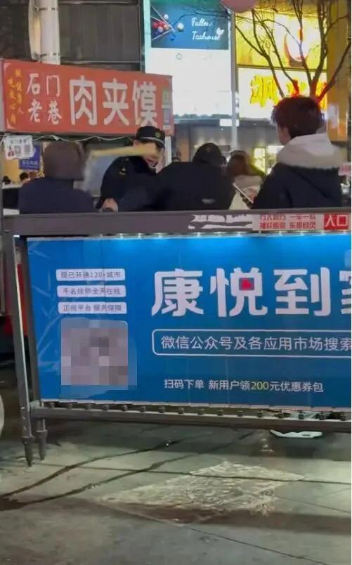 河北石家庄。几名城管人员围着一个卖肉夹馍的摊贩，忽然摊贩拿起折叠板凳砸向一人头