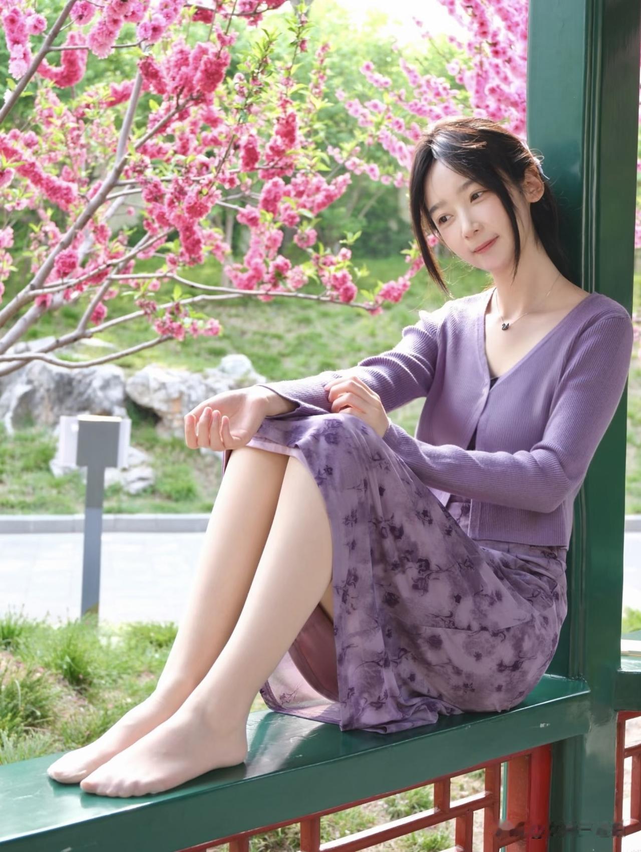 一个女孩坐在长椅上，背景是粉色的花。